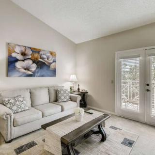 A cozy living room with a white sofa, floral artwork, and a wooden coffee table.