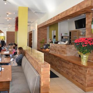 A modern restaurant interior with wooden accents, cozy seating areas, and decorative plants.