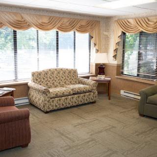 A cozy living room featuring a patterned sofa, an armchair, and large windows allowing natural light to flood the space.