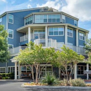 A modern, multi-story residential building surrounded by trees.