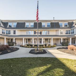 A symmetrical building with a central pathway and an American flag in front.