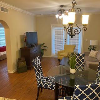 A cozy living and dining area with a mix of modern and classic decor, including a glass dining table, patterned chairs, and an elegant chandelier.