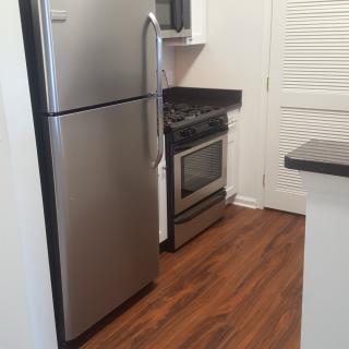 Modern kitchen with stainless steel appliances and wood flooring.