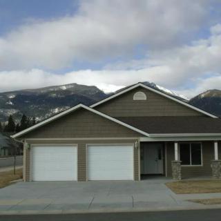 Suburban house with a double garage and mountain view on a cloudy day.