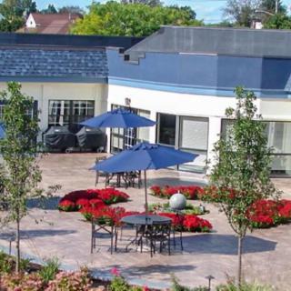 A comfortable outdoor patio area with tables, chairs, umbrellas, and surrounding vibrant flowers.