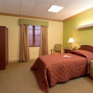 A cozy hotel room with a single bed and warm lighting.