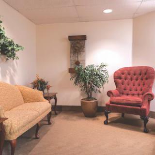 A cozy waiting area with a sofa, an armchair, and potted plants.
