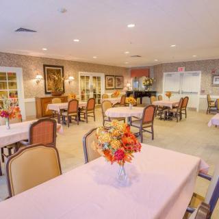 A well-lit dining area with neatly arranged tables and floral centerpieces.