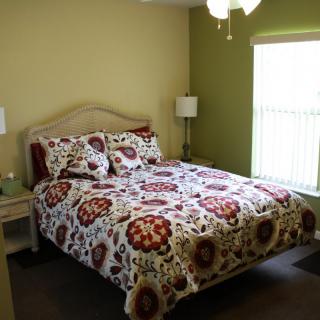 A cozy bedroom with patterned bedding and natural lighting.