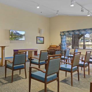 A meeting room setup with chairs arranged in rows, featuring a lectern and a television on the wall.