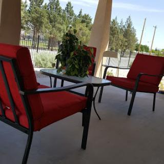 A cozy outdoor seating area with red cushioned chairs and a small table, perfect for relaxation.