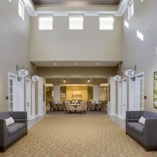 A spacious and modern lobby with high ceilings, featuring comfortable seating and bright natural lighting.