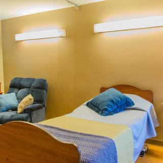 A cozy bedroom setup featuring a neatly made bed with blue pillows and a comfortable recliner chair.