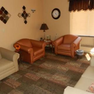 A cozy living room with two armchairs, a sofa, and decorative elements.