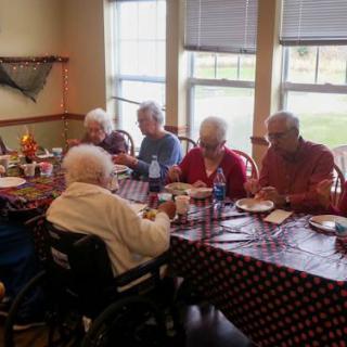 A group of seniors enjoying a meal together at a dining table indoors.