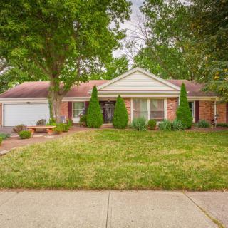 A suburban house with a well-maintained front yard and trees lining the property.