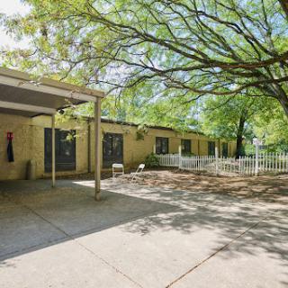 A cozy outdoor space featuring a patio shaded by a large tree, perfect for relaxation.