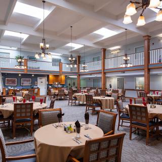 A spacious dining room with elegantly set tables and comfortable seating.