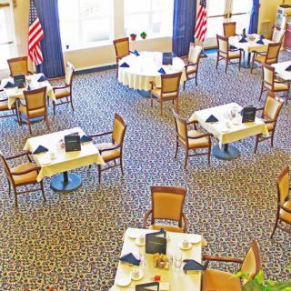 An empty dining area with neatly arranged tables and chairs, featuring prominent flag decorations.