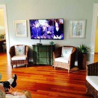 A cozy living room with a mounted television and wicker furniture.