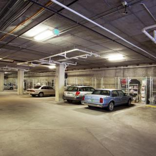 An underground parking garage with several parked cars and ample empty space.