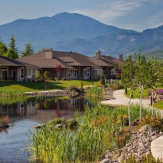 A picturesque landscape featuring houses by a tranquil lake with a mountain backdrop.