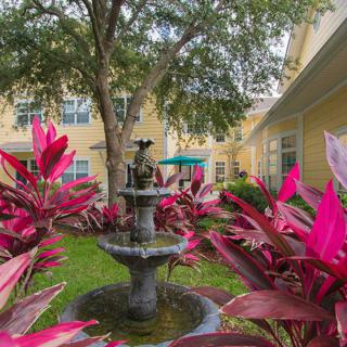 A serene courtyard garden featuring a central fountain surrounded by vibrant red foliage.