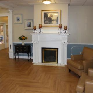 A cozy living room with a fireplace, decorated with artwork and classic furniture.