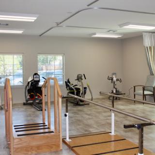 A well-equipped physical therapy room featuring various exercise machines and a wooden ramp for rehabilitation.