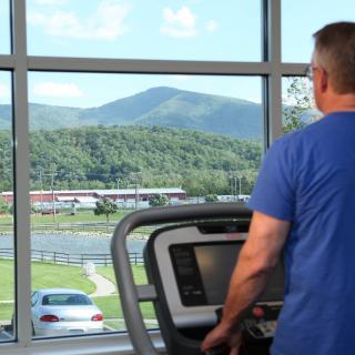 A person exercising on a treadmill with a scenic mountain view in the background.