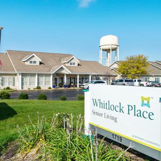 A view of the Whitlock Place senior living community with its distinctive signage and main building in the background.