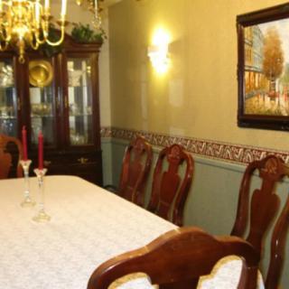 A traditional dining room with a table, chairs, chandelier, and decorative cabinet.