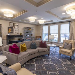 A modern and cozy living room featuring a curved sofa with colorful pillows, elegant lighting, and stylish decor.