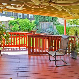 A cozy outdoor deck with a chair, wooden railing, and lush garden view.