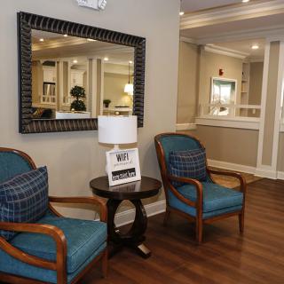 A cozy seating area with two armchairs and a mirror on the wall.