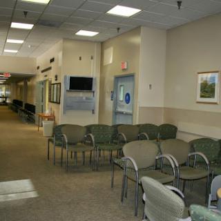 A quiet waiting room in a medical facility, featuring several chairs and a corridor leading to other areas.