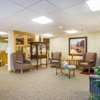 A cozy waiting room with comfortable chairs, a glass table, and artwork on the wall.