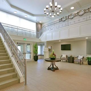 A modern lobby interior featuring a staircase, chandelier, and seating area.