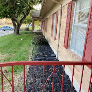 A view of a well-maintained exterior with landscaping, featuring grass and decorative black mulch alongside the building.
