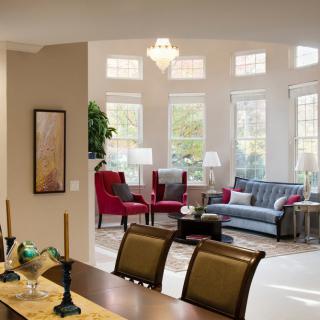 A stylish living and dining area with ample natural light flooding through large windows, featuring cozy seating and elegant decor.