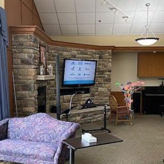 A cozy living room with a television, couch, and a brick accent wall.