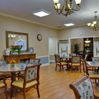A well-decorated dining room with floral upholstered chairs and elegant chandeliers.