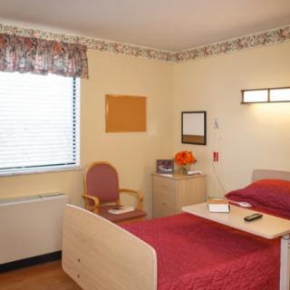 A neatly arranged hospital room with a bed, chair, and window.