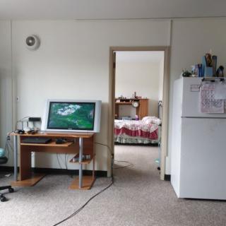 A cozy home workspace with a computer desk and adjoining bedroom.