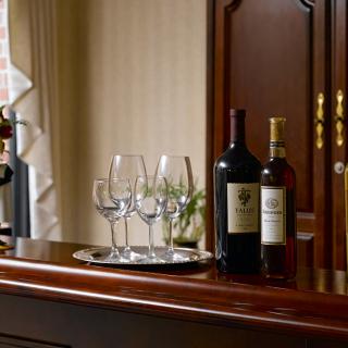A luxurious bar setup featuring wine bottles and glasses on a polished wooden counter.