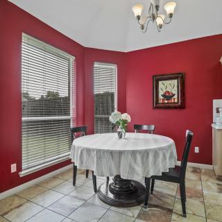 A cozy dining area with red walls and a round table set by large windows.