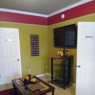 A cozy living room with colorful walls, a wall-mounted TV, and a neatly arranged coffee table.