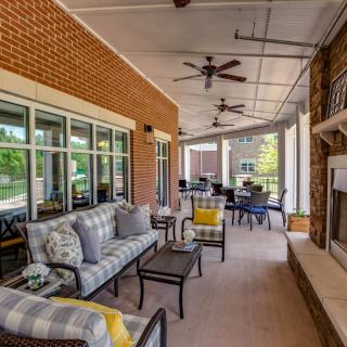 A cozy outdoor patio with comfortable seating, ceiling fans, and a fireplace.