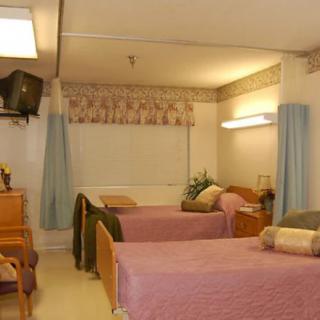 A hospital room with two beds, television, and furniture.