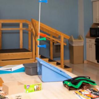 A cluttered playroom with toys scattered across the floor and a small indoor staircase.